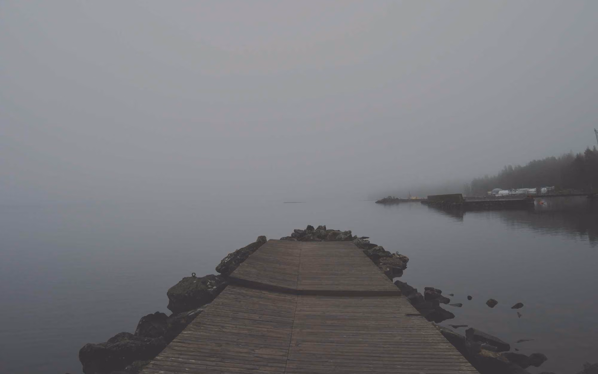 Pontão de madeira a entrar num mar coberto de nevoeiro